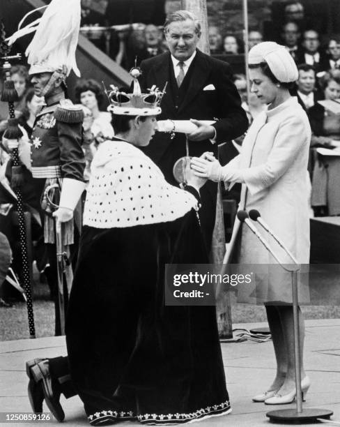 British Queen Elizabeth II holds the hands of her 20-year-old son Prince Charles during his investiture as Prince of Wales, on July 11 at Caernarfon...