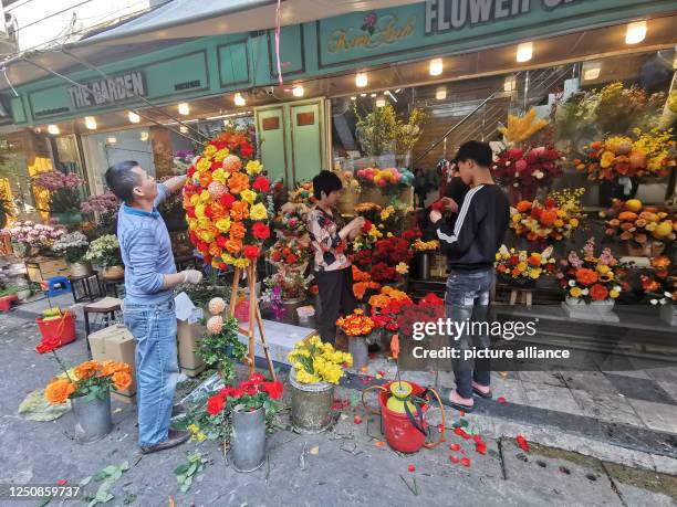February 2023, Vietnam, Hanoi: Vietnamese working on various flower arrangements in front of a flower store on a street in the Old Quarter. Photo:...