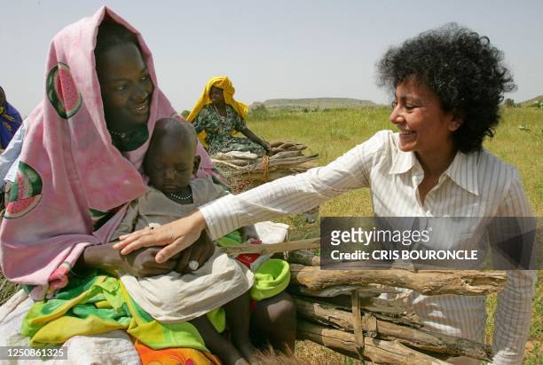 Amnesty International Secretary General Irene Khan taps on the hand of a Sudanese woman collecting firewood 17 September 2004 near the remote village...