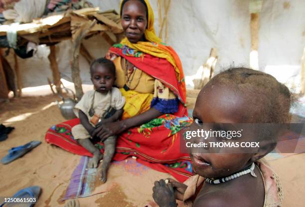 Sudanese refugees sit under a tent 26 June 2004 in Chad at the Iridimi refugee camp harbouring 15,000 refugees who fled the Darfur region where...