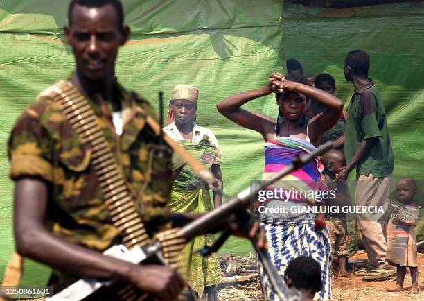 Burundian soldier patrols as Congolese refugees look on, 19 June 2004, at the Rugombo refugee Camp, 20 kms from the Congolese border. Almost 25,000...