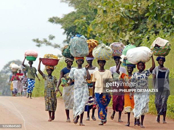 Malian-born women, who left their villages on the frontline for a safer place in towns held by rebel forces, walk 22 October 2002 on a road between...