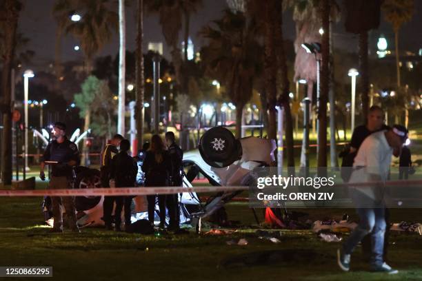 Israeli police gather around an overturned car at the site of an attack in Tel Aviv on April 7, 2023. - One man was killed and four people were...