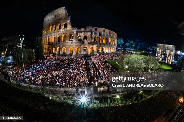 General view shows people gather by the Colosseum monument in Rome during the Way of the Cross prayer service in Rome on April 7, 2023 as part of...