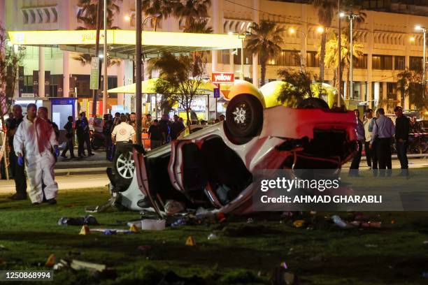 Israeli police gather next to a car used in a ramming attack in Tel Aviv on April 7, 2023. - One man was killed and four people were wounded in an...