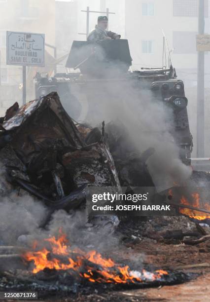 Lebanese soldier guards a position behind burning tires and burnt vehicules during a demonstration for wage increases in Beirut on May 7, 2008....