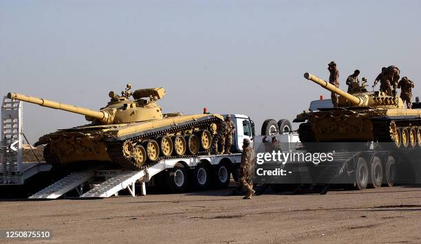 Two soviet-designed T-72 tanks roll off flat-bed trucks at an army compound in al-Taji, north of Baghdad, 12 November 2005. Iraq announced it had...