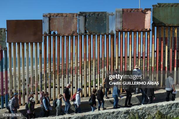 Advocates and activists walk along the border wall as they take part of a Holy Week ceremony at the Friendship Park on the border between Mexico and...