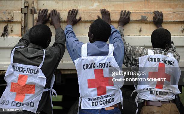 Congolese Red Cross workers help unload a truck during a food distribution for Internally Displaced People near a camp for IDPs in the town of...