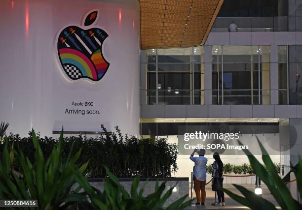 People are seen taking pictures of the soon-to-be launched Apple's first company-owned store in India inside the Jio World Drive mall at Bandra Kurla...