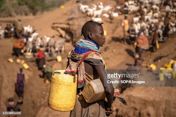 Woman of the Turkana tribe with plastic containers waiting to get water from a well. Climate change in East Africa is causing the worst drought in...
