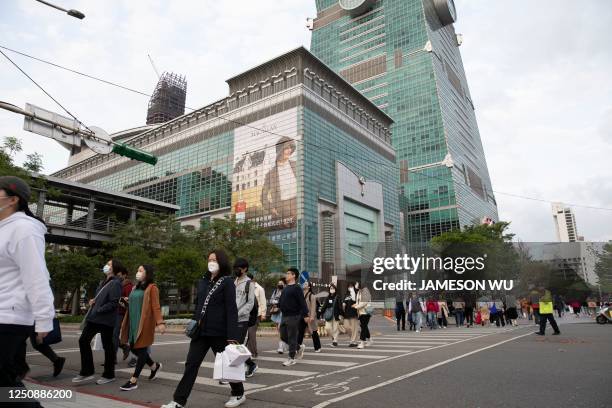 People walk along the street next to the Taipei 101 building in Taipei on April 8, 2023. - China launched military drills around Taiwan on Saturday,...