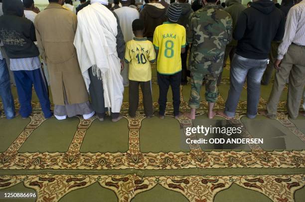 Rebel fighters in military fatigues and youngters in football T-shirts perform the Friday prayer in Ajdabiya's only open mosque on April 8, 2011 as...