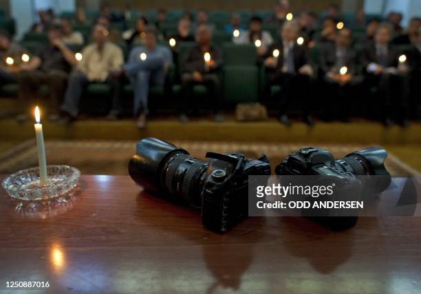 Light burns next to two cameras posed symbolicallly during a memorial service for slain photojournalists Tim Hetherington and Chris Hondros held in...