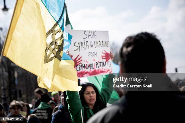 Woman holds a sign with the slogan words Save Syria & Ukraine from criminal Putin as people, many of them Ukrainians living in Berlin, protest in...