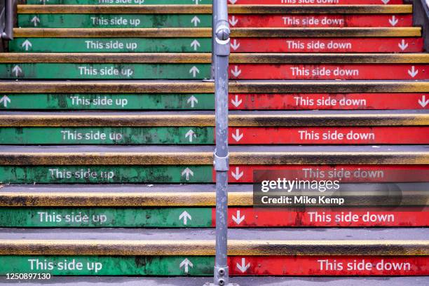 Steps up to Charing Cross station in red and green read 'This side up' and 'This side down' on 26th March 2023 in London, United Kingdom.