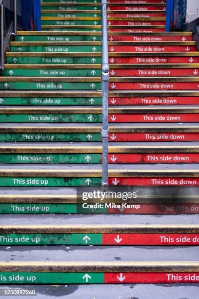 Steps up to Charing Cross station in red and green read 'This side up' and 'This side down' on 26th March 2023 in London, United Kingdom.