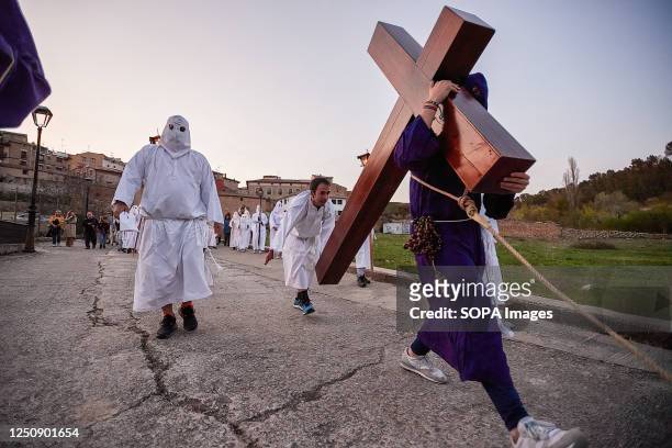 Penitent from the Brotherhood of the "Santa de la Vera Cruz", transports the Cross of Jesus Christ accompanied by another penitent breaking the...