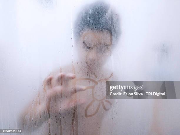 kid playing to draw on glass fogged by water vapor during hot bath - kids taking a shower stockfoto's en -beelden