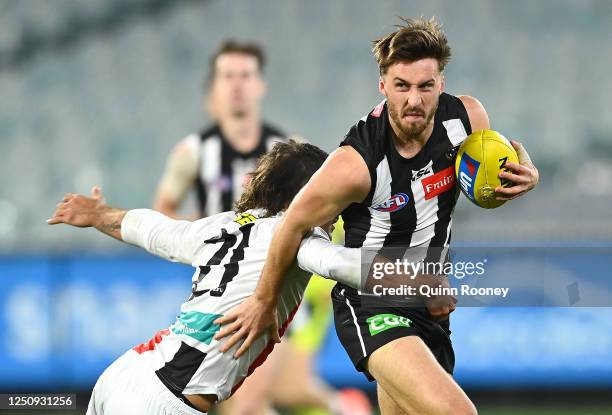 Tom Phillips of the Magpies breaks from a tackle by Ben Long of the Saints during the round 3 AFL match between the Collingwood Magpies and the St...