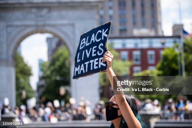 Protester wearing a mask cradles a sign that says, "Black Lives Matter" with the Washington Square arch behind them in Washington Square Park. This...