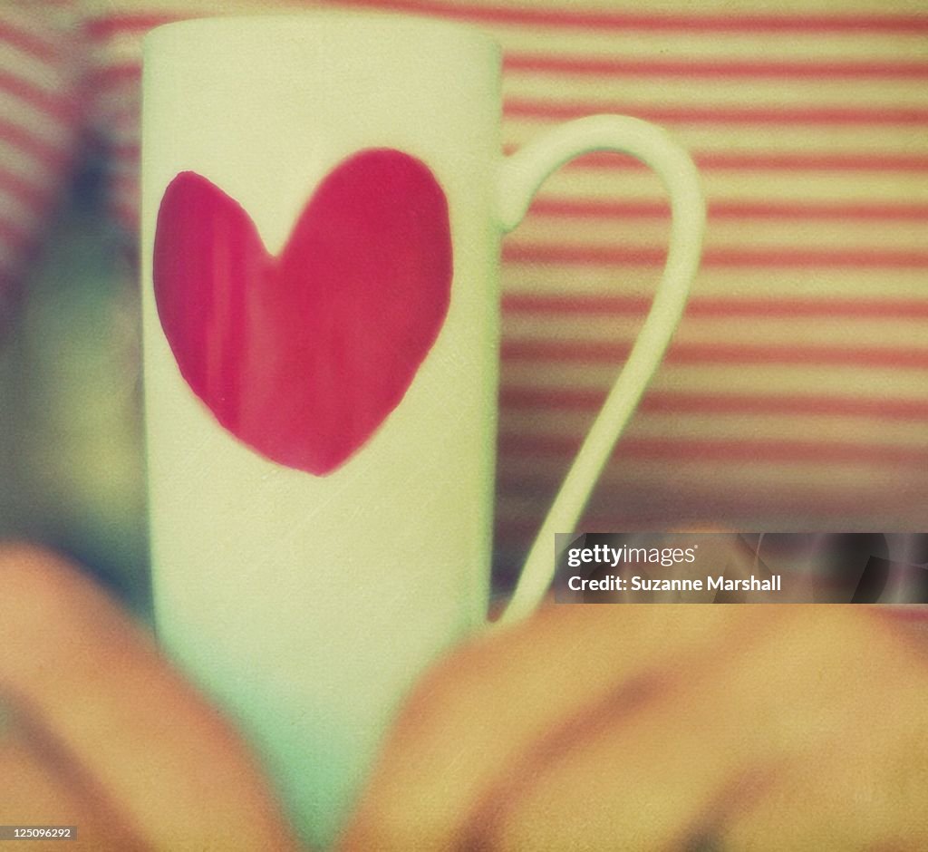 Hands holding heart mug