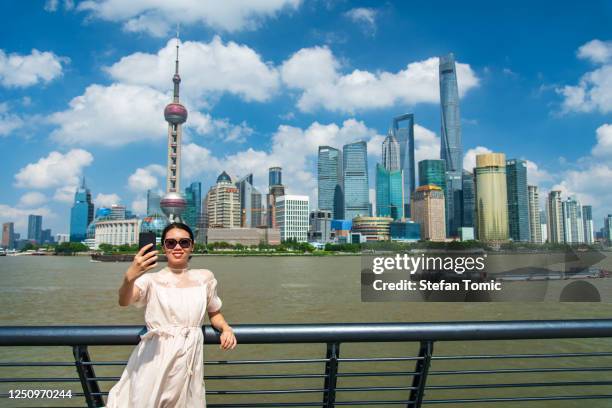 female tourist taking selfie at downtown shanghai and enjoying the skyline view from the bund promenade - shanghai calling stock pictures, royalty-free photos & images