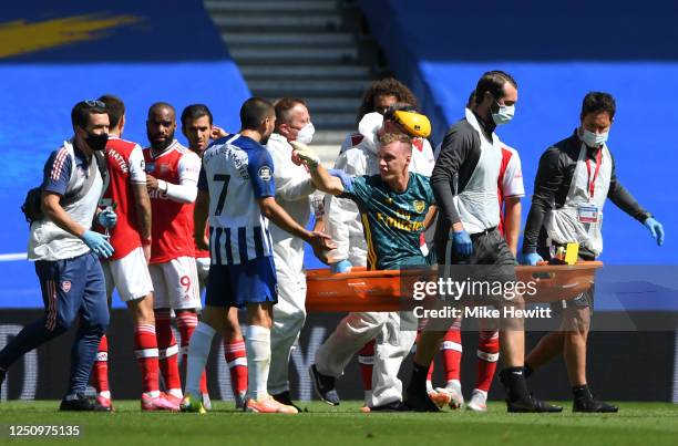 Bernd Leno of Arsenal points towards Neal Maupay of Brighton and Hove Albion as he is stretched off injured during the Premier League match between...