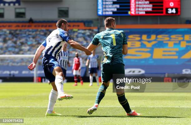 Bernd Leno of Arsenal attempts to collect the ball as he collides with Neal Maupay of Brighton and Hove Albion and later goes down injured during the...