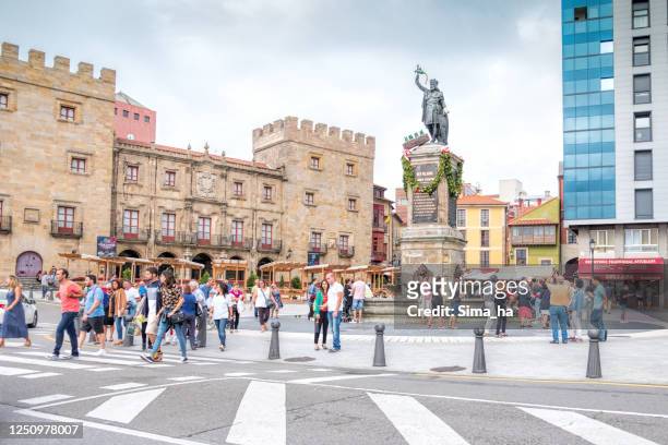 tourists walking near rex pelagius monument in the old city of gijon, spain. - gijon stock pictures, royalty-free photos & images