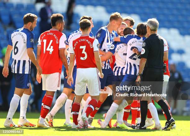 The Arsenal and Brighton and Hove Albion players clash as referee Martin Atkinson attempts to break them up during the Premier League match between...