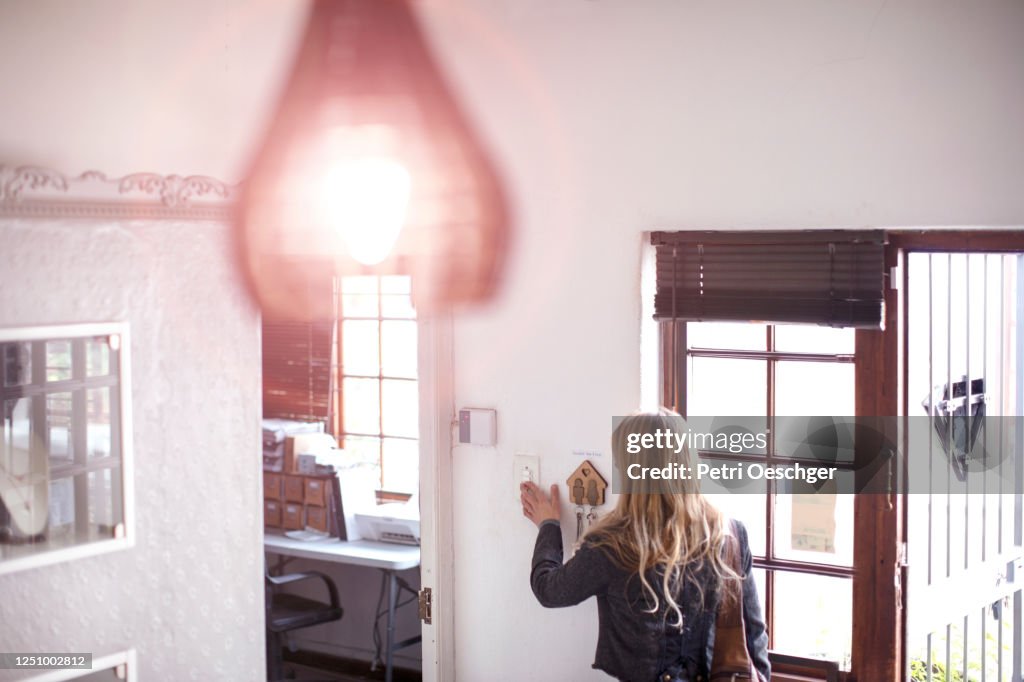Eine Kleinunternehmerin schaltet in ihrem Geschäft das Licht ein.