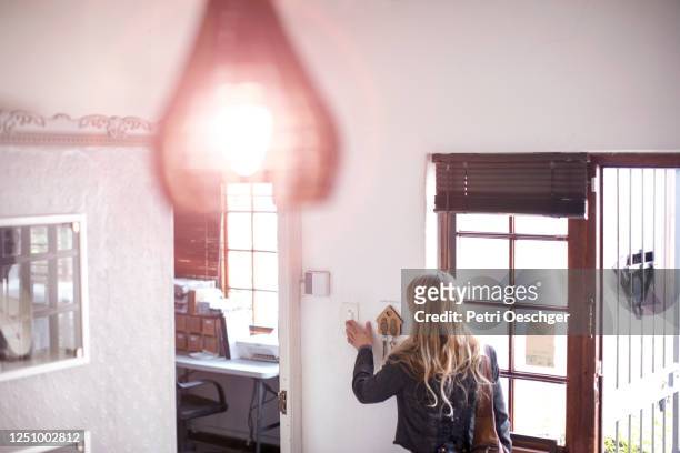 a small business owner turning on the lights in her shop. - ligado imagens e fotografias de stock