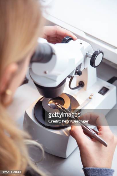 a jewelry designer grading the quality of a gemstone through a microscope. - diamond jeweller stock pictures, royalty-free photos & images