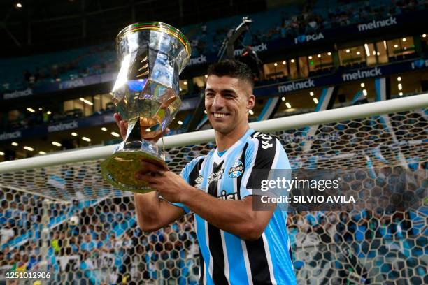 Gremio's Uruguayan forward Luis Suarez holds the trophy after winning the Rio Grande do Sul State Championship, better known as the Gaucho...