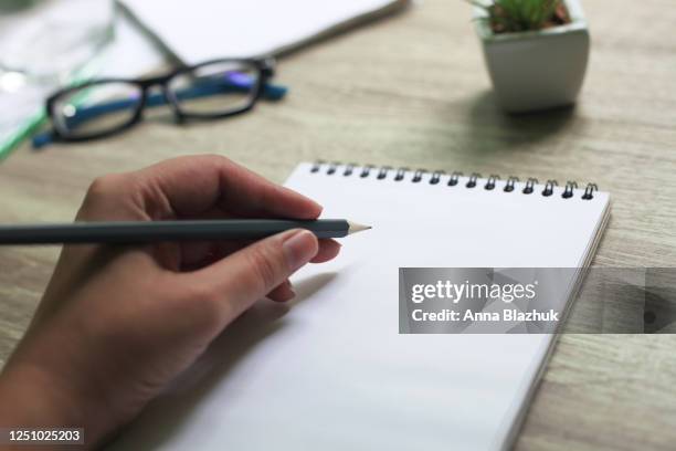 female hand with pencil writing in the notepad on desk. natural daylight. international lefthanders day. - left handed stock pictures, royalty-free photos & images