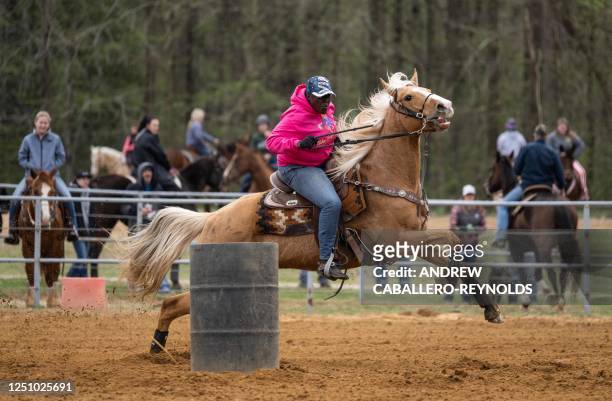 Karen Copeland reins her horse around a barrel during a local competition at the National Barrel Horse Association at Triple Creek Farm in Lothian,...