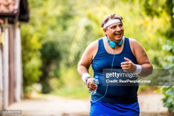 homem acima do peso correndo, exercitando- se, fazendo cardio no parque , ligeiramente acima do peso, perdendo peso - fat - fotografias e filmes do acervo