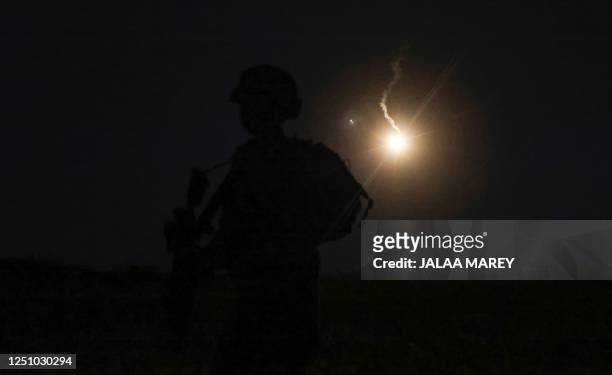 The silhouette of an Israeli soldier is outlined in the sky by a flare fired to search for a rocket that landed near Kibbutz Meitsar in the Israeli...