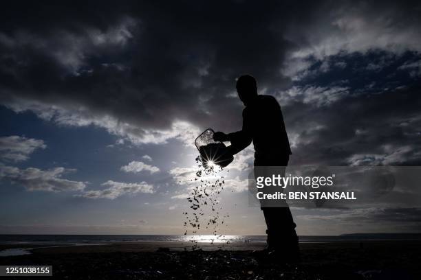Volunteer pours the contents of a bucket full of nurdles and microplastics onto a tarp during a beach clean on the Tregantle beach part of the...