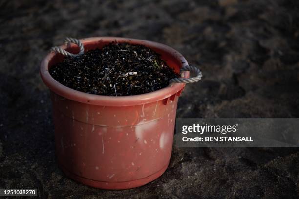 Photograph taken on February 26, 2023 shows a bucket full of nurdles and other micro-plastics waste collected during a beach clean organised on the...