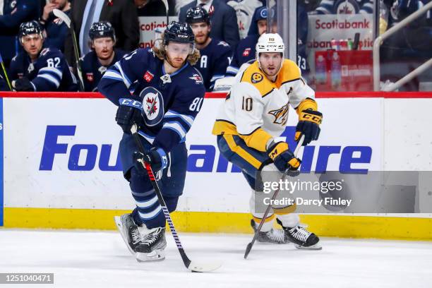 Kyle Connor of the Winnipeg Jets plays the puck down the ice as Colton Sissons of the Nashville Predators gives chase during second period action at...