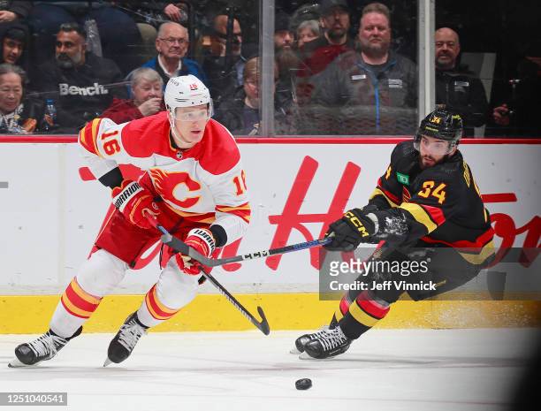 Phillip Di Giuseppe of the Vancouver Canucks and Nikita Zadorov of the Calgary Flames battle for the puck during the second period of their NHL game...