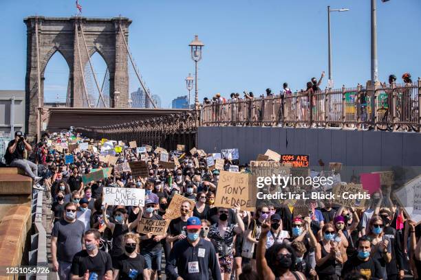 Thousands of protesters walk in a peaceful protest across the Brooklyn Bridge holding signs Brooklyn Bridge Arch in the background. This was part of...