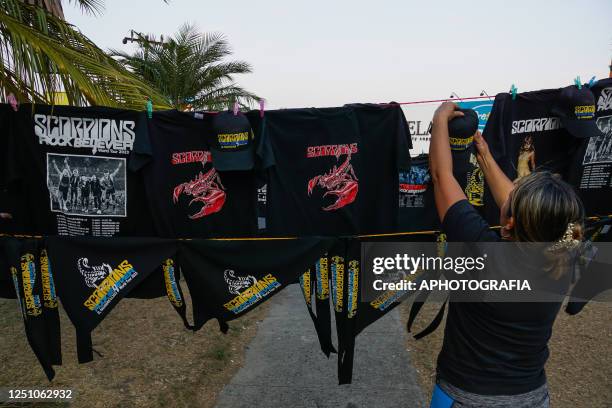 Woman hangs up shirts for the band Scorpions during a concert as part of the Rock Believer Tour 2023 at Cuscatlan stadium on April 08, 2023 in San...