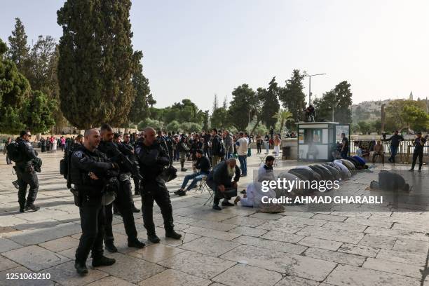 Muslim worshippers pray as Israeli security forces escort Jewish visitors at the Al-Aqsa mosque compound, also known as the Temple Mount complex to...
