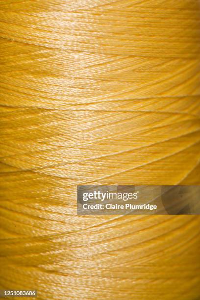 close up of a yellow reel of cotton thread - embroidery stock-fotos und bilder