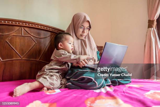 Mother using laptop in bedroom