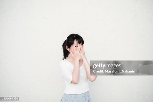 白い壁の前で笑顔でポーズをとるアジア人女性の写真 - obscured face ストックフォトと画像