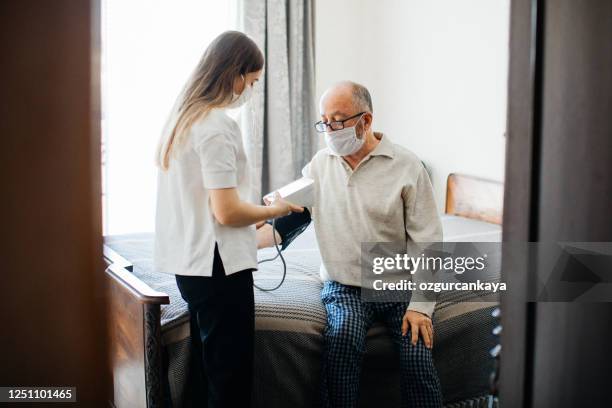 krankenschwester besucht senior männlich zu hause bei der blutdruckmessung - nurse with old male patient home care stock-fotos und bilder